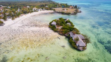 Yaz günbatımında okyanusun üzerinde bulunan çarpıcı bir otelin havadan görünüşü görülmeye değerdir. Afrika, Zanzibar 'da yer alan bu tepedeki manzara deniz manzaralı ahşap oteli, bir tekne ve gök mavisi suyu yakalar., 