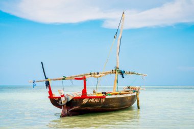 Geleneksel bir Zanzibar balıkçı teknesinin güzelliğini tecrübe edin. Tropik bir adanın sahilindeki berrak sularda dinleniyor. Yaz yolculuğu ve balıkçı tekneleri için ideal..