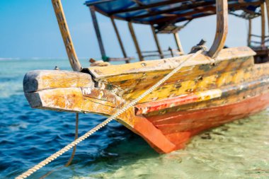 Tropik bir adanın yakınında, geleneksel bir Zanzibar balıkçı teknesi sahile yakın berrak sularda uzanıyor, yaz gezileri ve balıkçı tekneleri için mükemmel.
