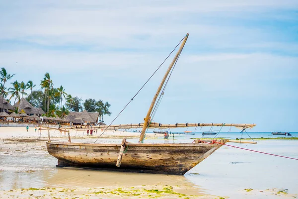 Experience the beauty of a traditional Zanzibar fishing boat as it rests in the clear waters near the beach of a tropical island, ideal for summer travel and fishing boats.