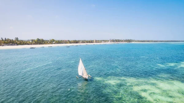 ザンジバルの熱帯の楽園は 日の出の砂のビーチで休んでいる漁船のこの空中ビューで生きています 澄んだ青い海 緑豊かなヤシの木 遠くにヨットがあります — ストック写真