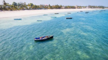 Zanzibar Adası beyaz kum, palmiye ağaçları ve turkuaz sularla güneşli bir yaz gününde kabarık bulutlu açık mavi bir gökyüzünün zeminine karşı çarpıcı bir tropikal plaja sahiptir. Bu resim gibi ortam rahatlatıcı bir tatil için mükemmel..