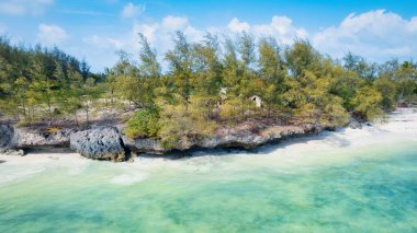 Zanzibar Adası beyaz kum, palmiye ağaçları ve turkuaz sularla güneşli bir yaz gününde kabarık bulutlu açık mavi bir gökyüzünün zeminine karşı çarpıcı bir tropikal plaja sahiptir. Bu resim gibi ortam rahatlatıcı bir tatil için mükemmel..