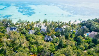 Zanzibar Adası beyaz kum, palmiye ağaçları ve turkuaz sularla güneşli bir yaz gününde kabarık bulutlu açık mavi bir gökyüzünün zeminine karşı çarpıcı bir tropikal plaja sahiptir. Bu resim gibi ortam rahatlatıcı bir tatil için mükemmel..