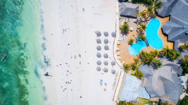 Kendinizi Zanzibar Adası 'nın tropikal plajının doğal güzelliğine bırakın. Beyaz kumları, sallanan palmiye ağaçları ve kristal berrak turkuaz sularıyla güneşli bir yaz gününde mavi gökyüzü ve tüylü bulutlar karşısında.. 