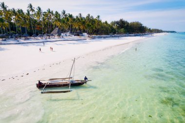 Kendinizi Zanzibar Adası 'nın tropikal plajının doğal güzelliğine bırakın. Beyaz kumları, sallanan palmiye ağaçları ve kristal berrak turkuaz sularıyla güneşli bir yaz gününde mavi gökyüzü ve tüylü bulutlar karşısında.. 