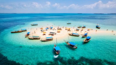 Kendinizi Zanzibar Adası 'nın tropikal plajının doğal güzelliğine bırakın. Beyaz kumları, sallanan palmiye ağaçları ve kristal berrak turkuaz sularıyla güneşli bir yaz gününde mavi gökyüzü ve tüylü bulutlar karşısında.. 