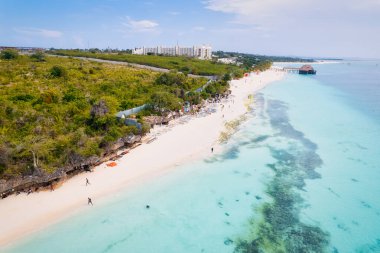 Beyaz kumlu, sallanan palmiye ağaçları ve berrak turkuaz sularıyla güneşli bir yaz gününde mavi gökyüzü ve kabarık bulutları olan tropikal bir cennete kaçmak. Zanzibar Adası en iyisi. 