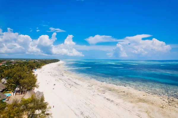 Kendinizi Zanzibar Adası 'nın tropikal plajının doğal güzelliğine bırakın. Beyaz kumları, sallanan palmiye ağaçları ve kristal berrak turkuaz sularıyla güneşli bir yaz gününde mavi gökyüzü ve tüylü bulutlar karşısında.. 