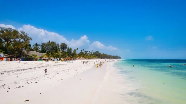 stock image Immerse yourself in the natural beauty of Zanzibar Island's tropical beach, with its white sand, swaying palm trees, and crystal-clear turquoise waters against a blue sky with fluffy clouds on a sunny summer day. 