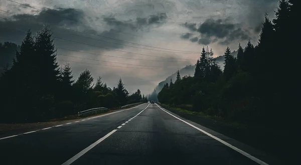 journey to the mountains on the highway through the dark forest