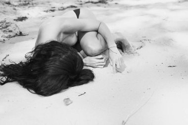 Deniz kıyısında çıplak bir kadın yatıyordu. Monokrom manzaralı fotoğrafçılık. Yaz. Arka planda kumlu zemini olan bir kadın resmi. Yüksek kalite duvar kağıdı. Reklamlar için fotoğraf konsepti, seyahat blogu, dergi, makale