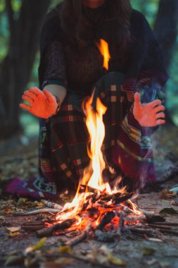 Bayan ve kamp ateşi manzaralı fotoğrafçılık. Kamp ve dinlenme. Arka planda yaz ormanı olan bir kadın resmi. Yüksek kalite duvar kağıdı. Reklamlar için fotoğraf konsepti, seyahat blogu, dergi, makale