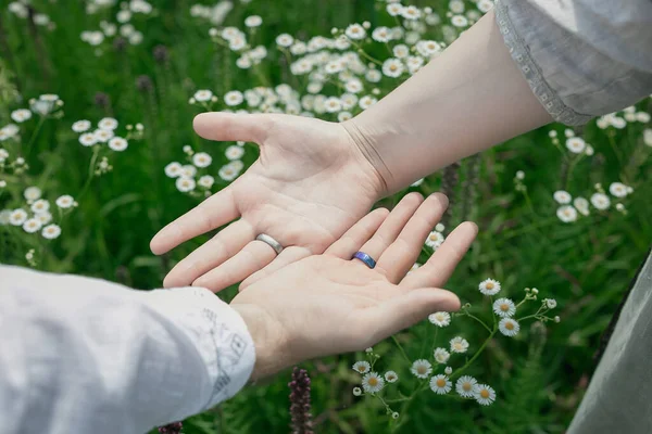 Alyans konsepti fotoğrafını kapat. Avuçlar yukarı. Eşler. Arka planda çiçek açan çayır fotoğrafçılığı. Duvar kağıdı, seyahat günlüğü, dergi, makale için yüksek kaliteli resim