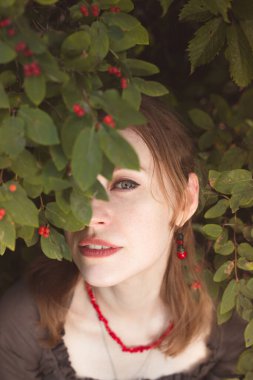 Böğürtlen yaprakları portresini dikizleyen bir kadın. Yaz zamanı. Yakın plan ön plan fotoğrafçılığı bulanık arkaplan. Reklamlar için yüksek kaliteli fotoğraf, seyahat blogu, dergi, makale