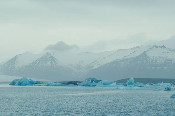 山の風景写真に対して海の氷山 背景に灰色の空と美しい自然の風景写真 牧歌的なシーン 旅行ブログ 記事のための高品質の画像 — ストック写真