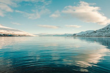 Sahil manzaralı karlı dağlarla kaplı bir deniz koyunda. Arka planda gökyüzü olan güzel doğa fotoğrafçılığı. Idyllic sahne. Duvar kağıdı, seyahat günlüğü, dergi, makale için yüksek kaliteli resim