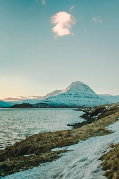 Deniz kıyısı yakınlarındaki karlı dağ manzarası fotoğrafı. Arka planda bulutlu gökyüzü olan güzel doğa manzara fotoğrafçılığı. Idyllic sahne. Duvar kağıdı, seyahat günlüğü, dergi, makale için yüksek kaliteli resim