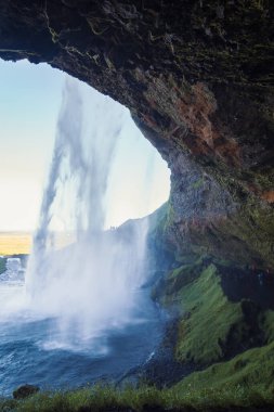 Muhteşem şelale manzarasının altındaki mağarada. Arka planda vadi olan güzel doğa manzarası fotoğrafçılığı. Idyllic sahne. Duvar kağıdı, seyahat günlüğü, dergi, makale için yüksek kaliteli resim