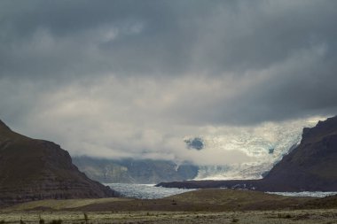 Dağlık arazi fotoğrafında Skeidararjokull buzulu. Arka planda bulutlu gökyüzü olan güzel doğa manzara fotoğrafçılığı. Idyllic sahne. Duvar kağıdı, seyahat günlüğü ve dergi için yüksek kaliteli resim