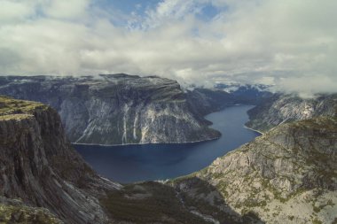 Dağların dibindeki sakin nehir manzarası. Arka planda bulutlu gökyüzü olan güzel doğa manzara fotoğrafçılığı. Idyllic sahne. Duvar kağıdı, seyahat günlüğü, dergi, makale için yüksek kaliteli resim
