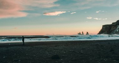 Okyanus sahili manzarasında yalnız bir insan. Arka planda günbatımı gökyüzü olan güzel doğa fotoğrafçılığı. Idyllic sahne. Duvar kağıdı, seyahat günlüğü, dergi, makale için yüksek kaliteli resim