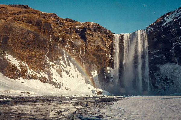 Skogafoss waterfall with rainbow landscape photo. Beautiful nature scenery photography with clear sky on background. Idyllic scene. High quality picture for wallpaper, travel blog, magazine, article