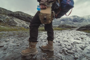 Dağ deresi manzaralı fotoğrafçılıkta yürüyen bir kadın. Arka planda bulutlu gökyüzü olan birinin resmi. Yüksek kalite duvar kağıdı. Reklamlar için fotoğraf konsepti, seyahat blogu, dergi, makale