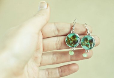 Yuvarlak küpeler gösteren yakın plan kadın konsept fotoğraflı. Arka planda bej duvar olan ilk kişi fotoğrafçılığı. Duvar kağıdı, seyahat günlüğü, dergi, makale için yüksek kaliteli resim