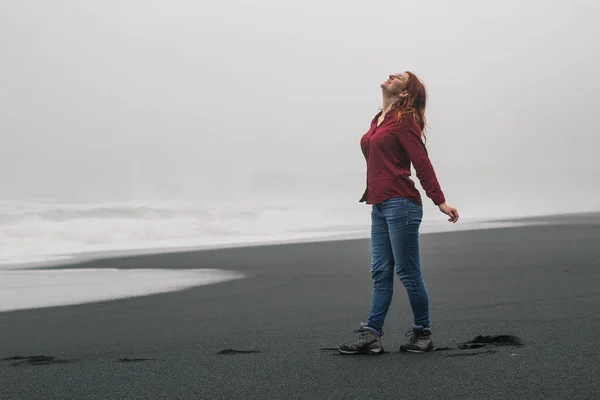 空の黒いビーチの風光明媚な写真に喜びの女性 背景に嵐の海を持つ人の写真 高品質の壁紙 旅行ブログ 記事のための写真のコンセプト — ストック写真
