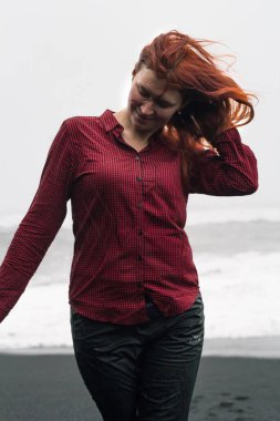 Close up young woman posing on Iceland beach portrait picture. Closeup front view photography with stormy ocean on background. High quality photo for ads, travel blog, magazine, article