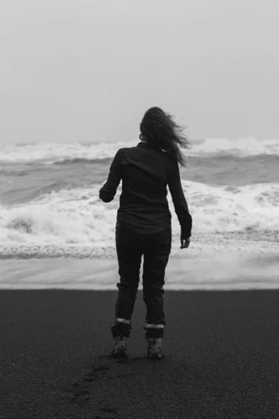 レイニスフィヤラビーチでの女性のモノクロの風景写真 背景に嵐の海を持つ人の写真 高品質の壁紙 旅行ブログ 記事のための写真のコンセプト — ストック写真