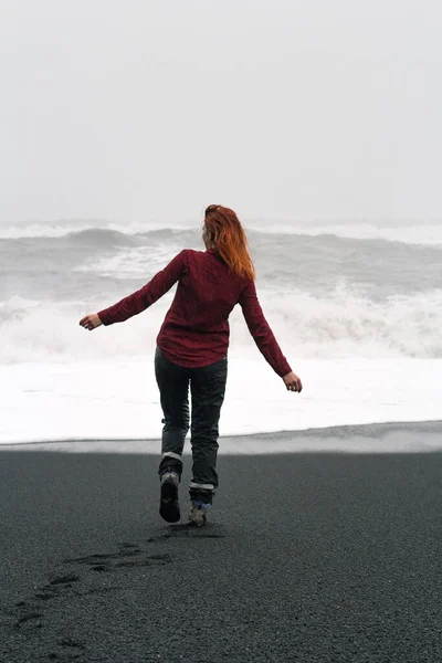 赤毛の女性の北のビーチの風光明媚な写真に沿って歩いてください 背景に嵐の海を持つ人の写真 高品質の壁紙 旅行ブログ 記事のための写真のコンセプト — ストック写真