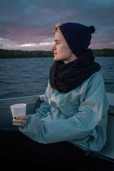 Close up relaxed lady with cup in boat portrait picture. Closeup side view photography with large lake at sunset on background. High quality photo for ads, travel blog, magazine, article