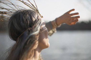 Close up middle age woman hiding from sun with palm portrait picture. Looking at lake. Closeup rear view photography with blurred background. High quality photo for ads, travel blog, magazine, article