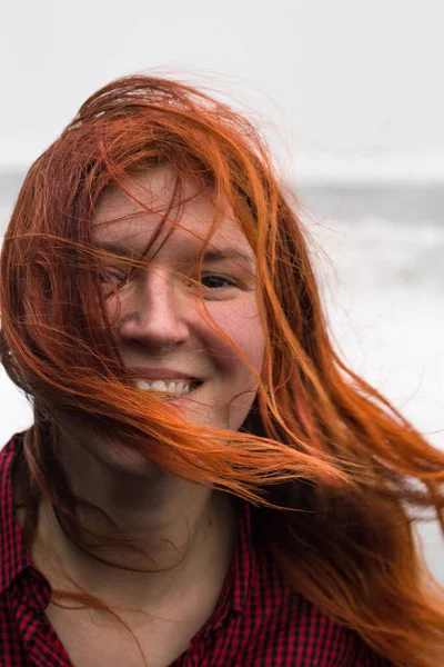 Close up happy lady with red hair waving in wind portrait picture. Closeup front view photography with blurry background. High quality photo for ads, travel blog, magazine, article