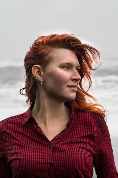 赤いシャツの屋外の肖像画の写真で魅力的な女性を閉じます 嵐の海を背景に閉鎖側のビューの写真 旅行ブログ 記事のための高品質の写真 — ストック写真