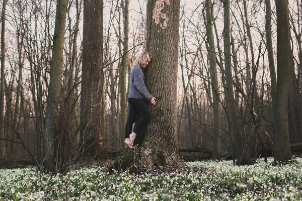 ブロンドの女性の大きな木の幹の風光明媚な写真を抱いている 背景に深い森を持つ人の写真 高品質の壁紙 旅行ブログ 記事のための写真のコンセプト — ストック写真