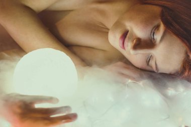 Close up tranquil woman holding light sphere portrait picture. Closeup side view photography with glowing surface blurred background. High quality photo for ads, travel blog, magazine, article