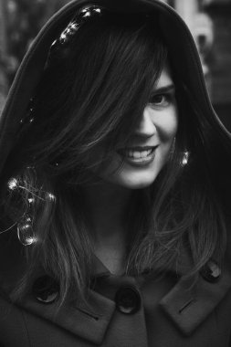 Close up pretty lady with hood and lights monochrome portrait picture. Closeup front view photography with blurry background. High quality photo for ads, travel blog, magazine, article