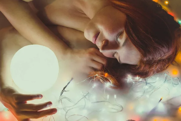 Close up sleeping lady with magical sphere portrait picture. Closeup side view photography with glowing fairy lights on background. High quality photo for ads, travel blog, magazine, article