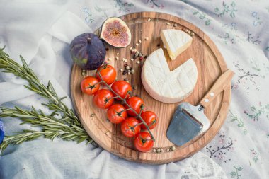 Close up round picnic cheese platter with tomatoes and figs concept photo. Top view photography with blurred background. High quality picture for wallpaper, travel blog, magazine, article
