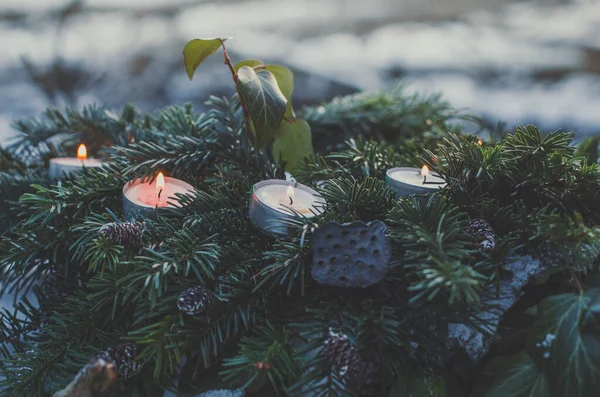Close up tealight candles in evergreen pine branches concept photo. Front view photography with blurred wintertime background. High quality picture for wallpaper, travel blog, magazine, article