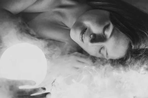 Close up woman with bright sphere in smoke monochrome portrait picture. Closeup side view photography with fairy lights on background. High quality photo for ads, travel blog, magazine, article