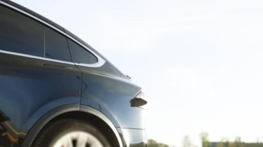 Businessman plugging in charging cable to to electric vehicle. Male hand inserts power connector into EV car and charges batteries, uses smartwatch for activates start charging