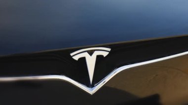 Lviv, Ukrayna - 17 Ekim 2022: Tesla Model X ekose logo rozetini kapatın. Siyah bir arabanın ön kaputunda Tesla logosu rozeti. TESLA logosu elektrikli arabanın yakın çekim görüntüsü.