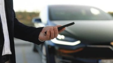 İşadamı mobil uygulama kullanarak otomatik çalışan bir elektrikli arabayı kontrol ediyor. Otonom otomatik pilot sürücüsüz araba. Akıllı telefon uygulaması. Algılayıcı tarama yolu ileride araçlar için, tehlike, hız limitleri
