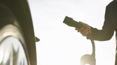 Tanınmayan işadamı elektrik kablosunu elektrikli araca bağlıyor. Erkek el güç bağlantısını EV arabaya yerleştirir ve pilleri şarj eder, aktifleştirmek için akıllı kaset kullanır