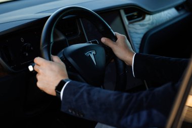 Lviv, Ukrayna - 17 Ekim 2022: Tesla X modeli. Genç kendine güvenen iş adamı harita navigasyon ses asistanı uyarı uygulaması görüntüleme teknolojisi kullanıyor. Arabanın içi..