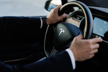 Lviv, Ukrayna - 17 Ekim 2022: Tesla X modeli. Harita navigasyon ses asistanı uygulama görüntüleme teknolojisi kullanan kendine güvenen genç iş adamının arka görüntüsü. Arabanın içi..
